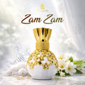 Perfume bottle with gold design and 'Zam Zam' branding on a white background with flowers.