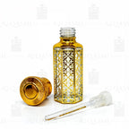 Decorative gold and clear glass perfume bottle with dropper on a white background. 12ML